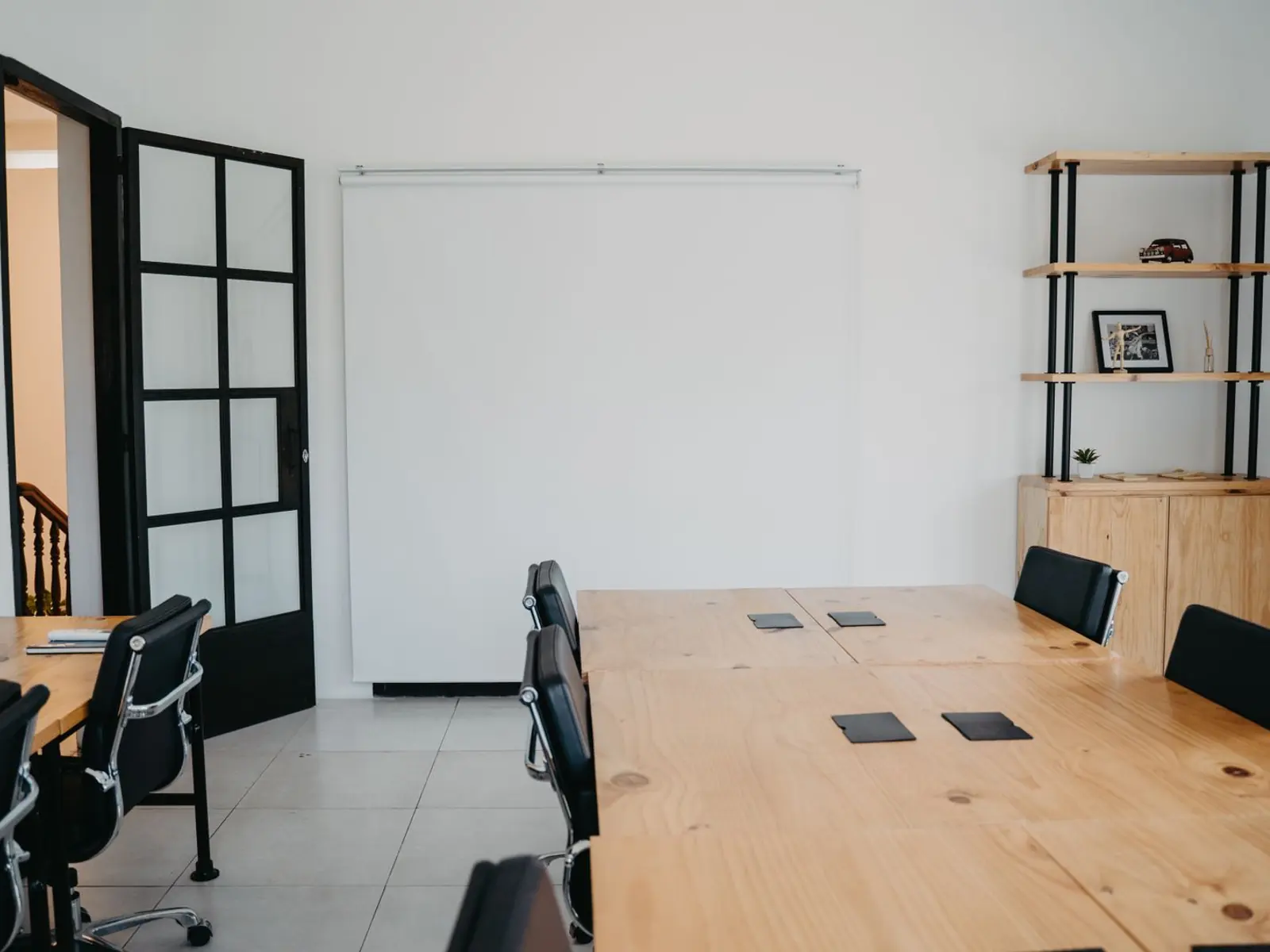 Sala de reuniones de un despacho con mesa de madera, sillas y la puerta abierta a la entrada