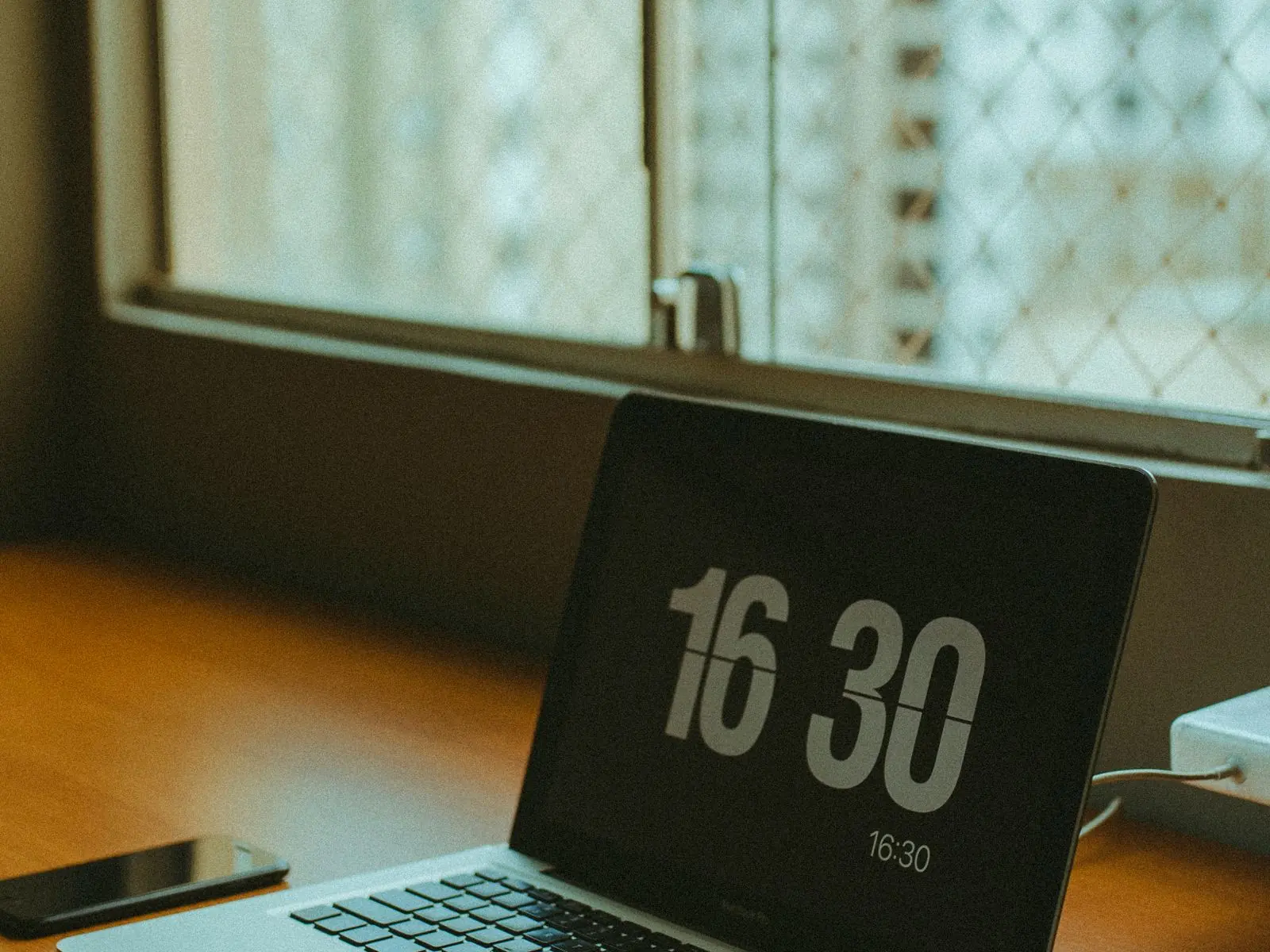 Ordenador portátil abierto sobre una mesa de trabajo junto a la ventana, preparado para una reunión por videoconferencia