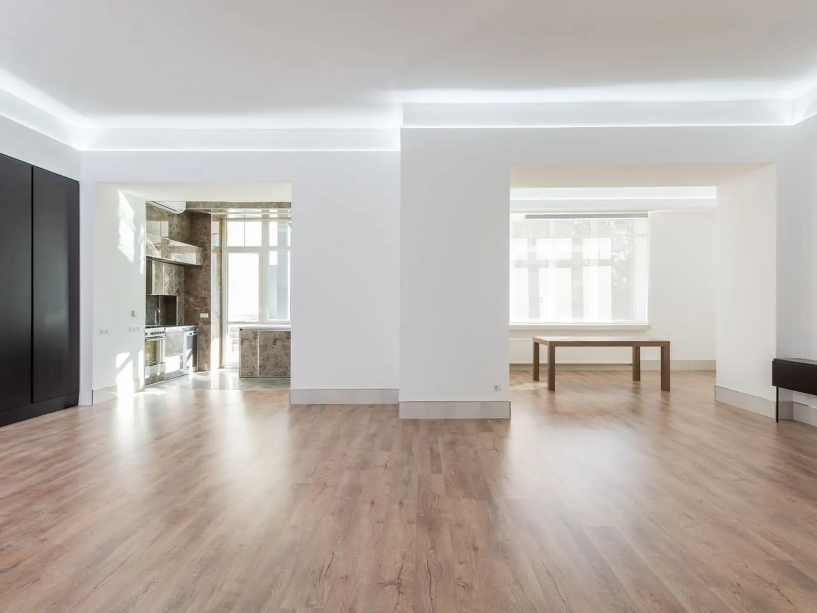 Salón vacío de una vivienda recién desocupada, con el suelo de madera y luz natural